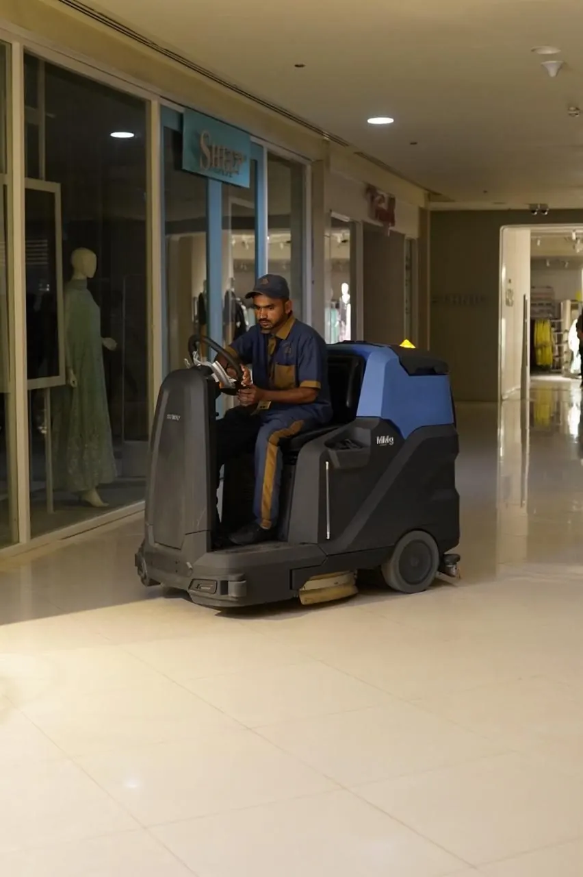 Ride-on floor scrubber passing retail storefronts